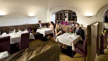 A restaurant with multiple tables and booths, each set with wine glasses, plates, and cutlery.