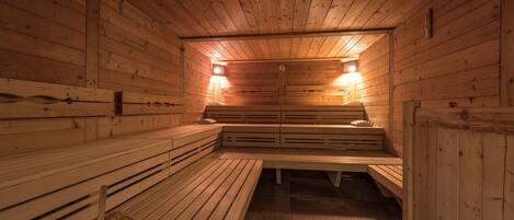 Una sauna con bancos de madera, incluyendo un banco central, y una lámpara en el techo.