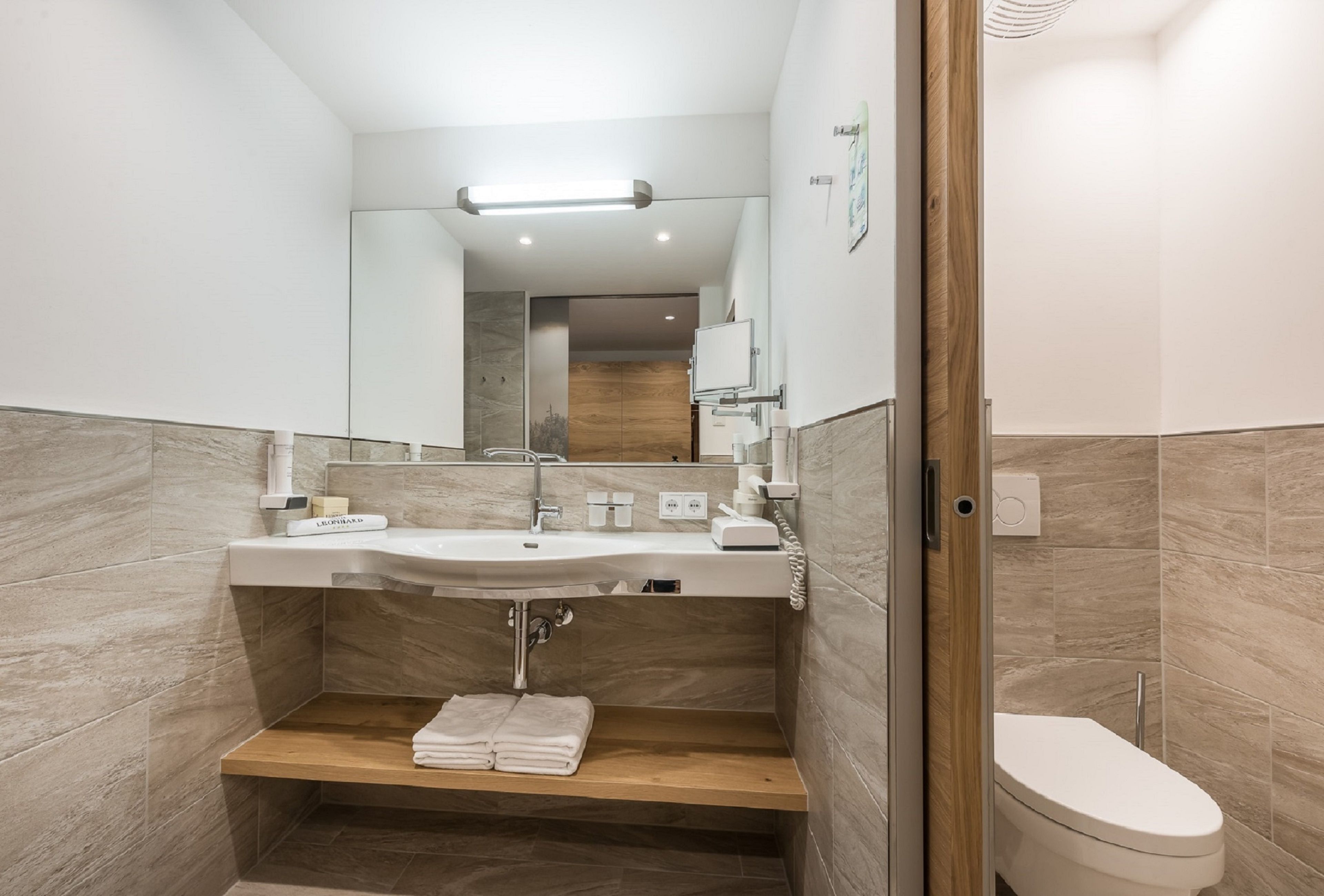 A modern bathroom with a sink, mirror, and toilet.