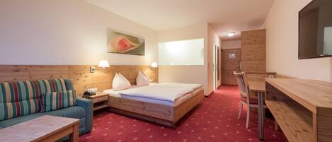 A hotel room with a bed, a sofa, a desk, and a TV.
