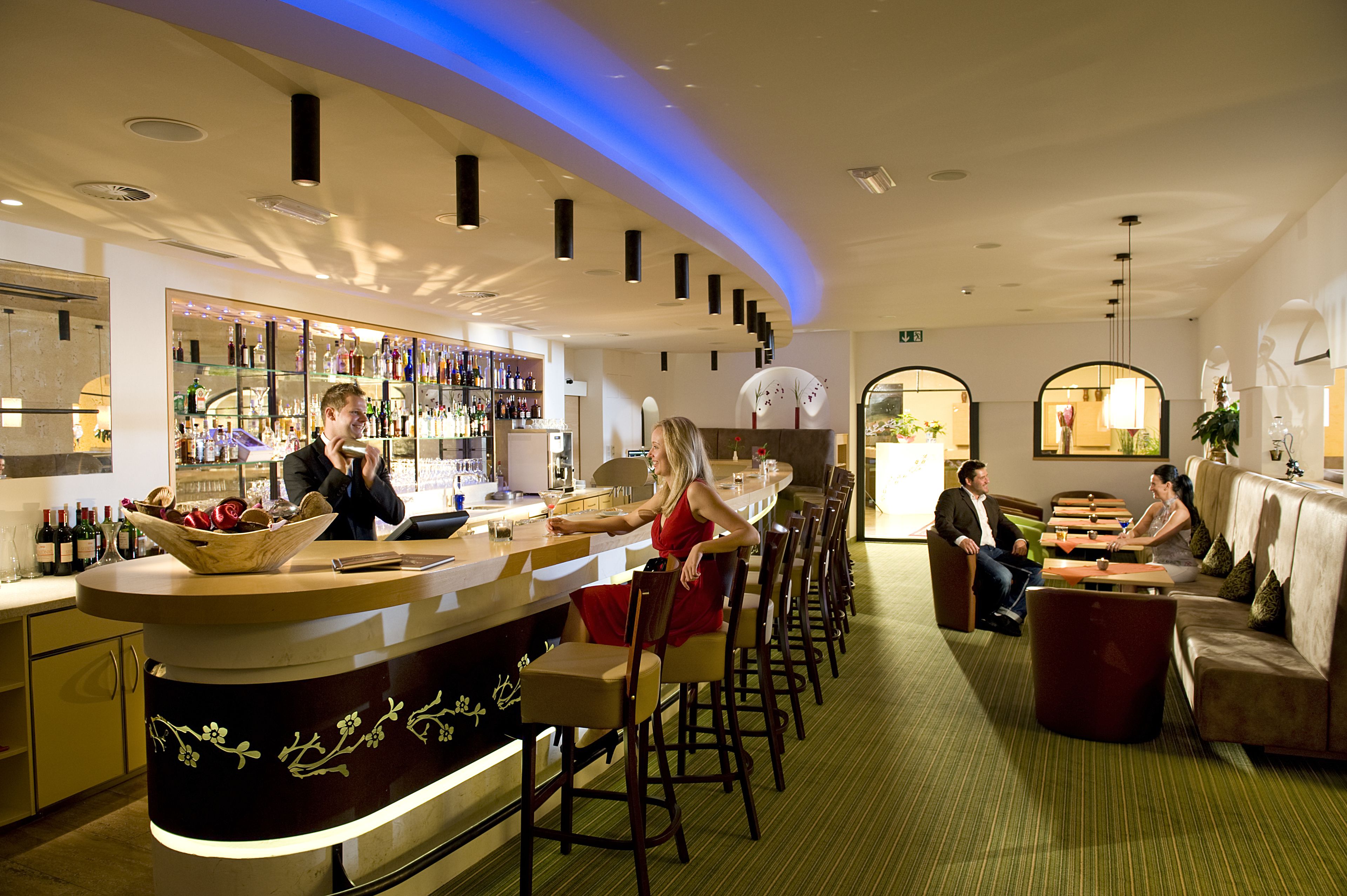 A bar area with a curved counter, seating for guests, and a visible wine rack.