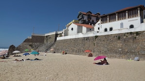 A beach with stone walls and a building with balconies. - Casa Ceedina B&B & Beauty (Batalha)