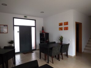 A modern dining area with a dark wooden table and chairs, a black bookshelf, and a potted plant. - Casa Ceedina B&B & Beauty (Batalha)