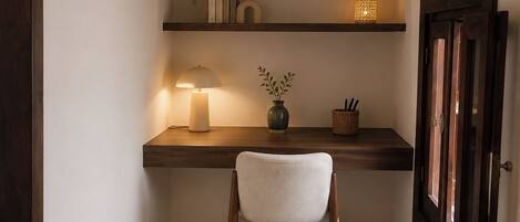 A cozy corner with a desk, chair, and shelves with decorative items.
