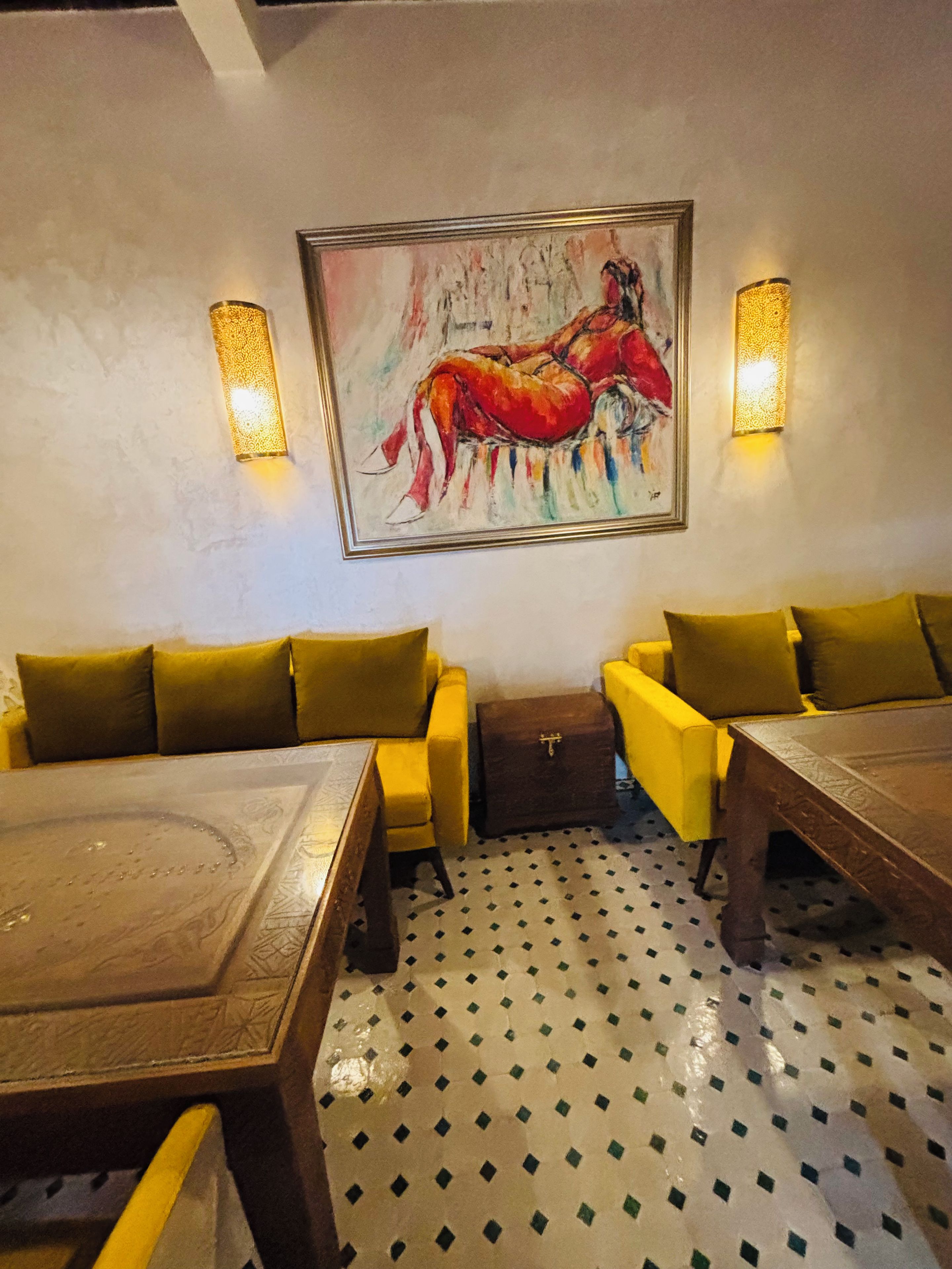 A dining area with yellow sofas, a wooden table, and a patterned floor.