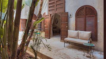 A traditional courtyard with wooden doors, a bench, and a small table.