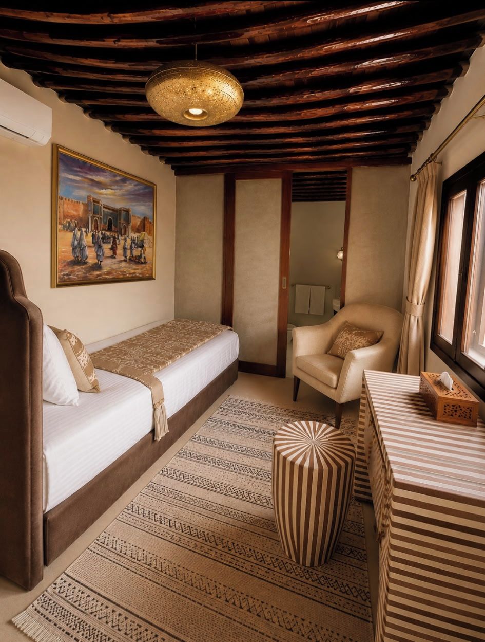 Una habitación con cama, una silla, un tapete y un cuadro en la pared.