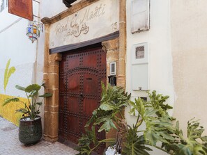A traditional wooden door with a metal lock, a potted plant in front, and a sign above the door. - Riad El Maâti (Rabat)