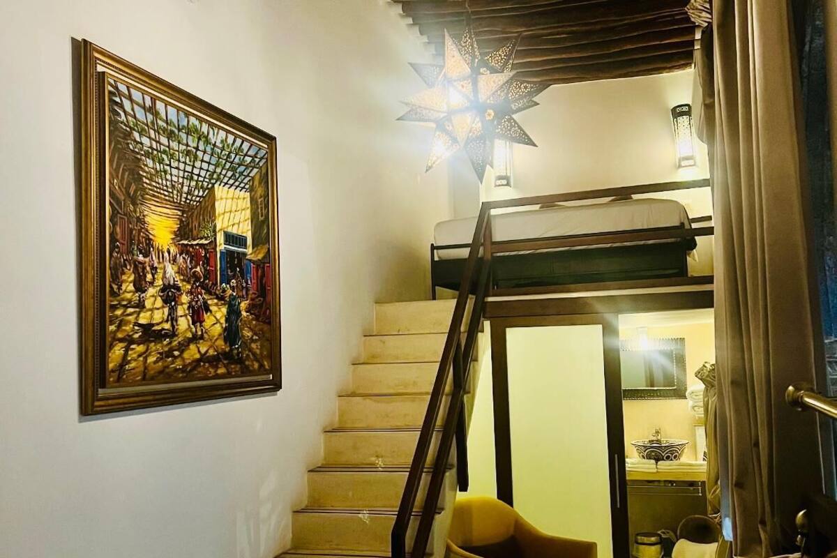 A staircase leading to a bedroom with a bed, a nightstand, and a bathroom visible in the background.