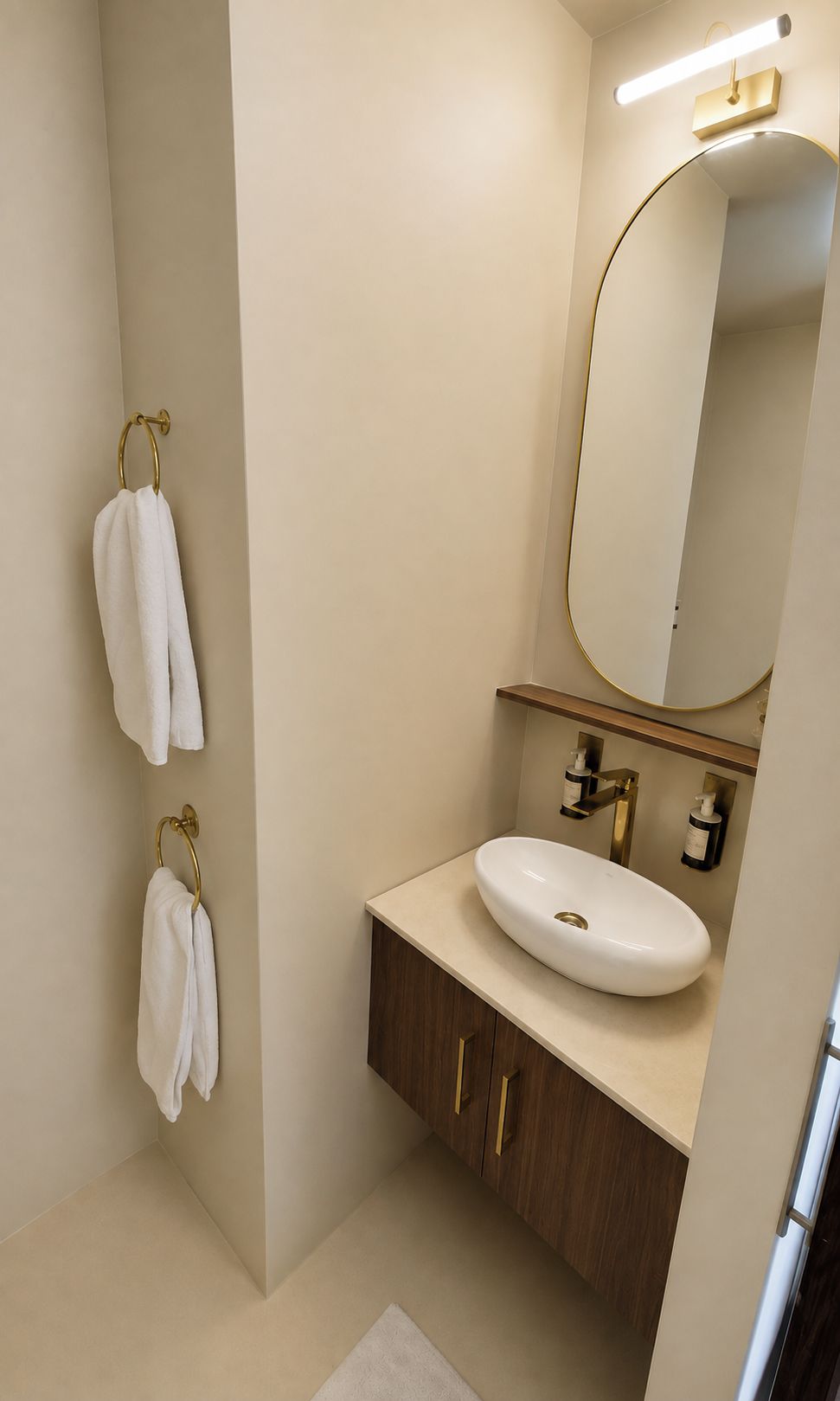 A modern bathroom with a white sink, gold fixtures, and a large mirror.