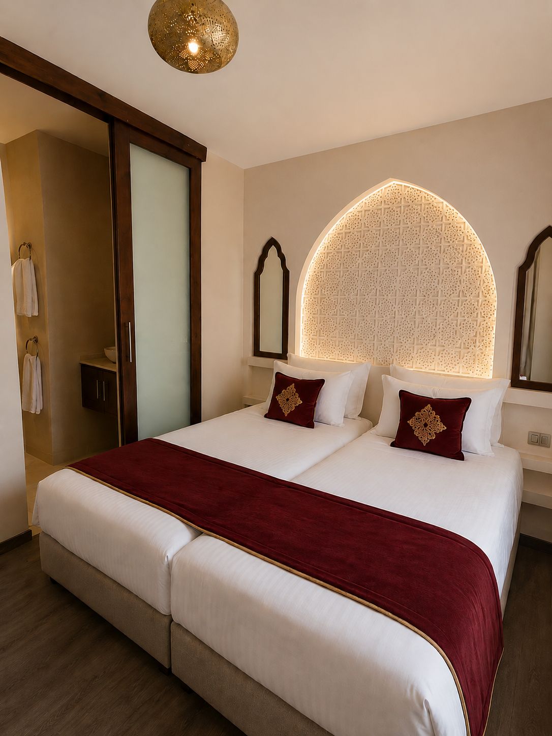 A hotel room with a large bed, a wooden wardrobe, a mirror, and a decorative ceiling light.