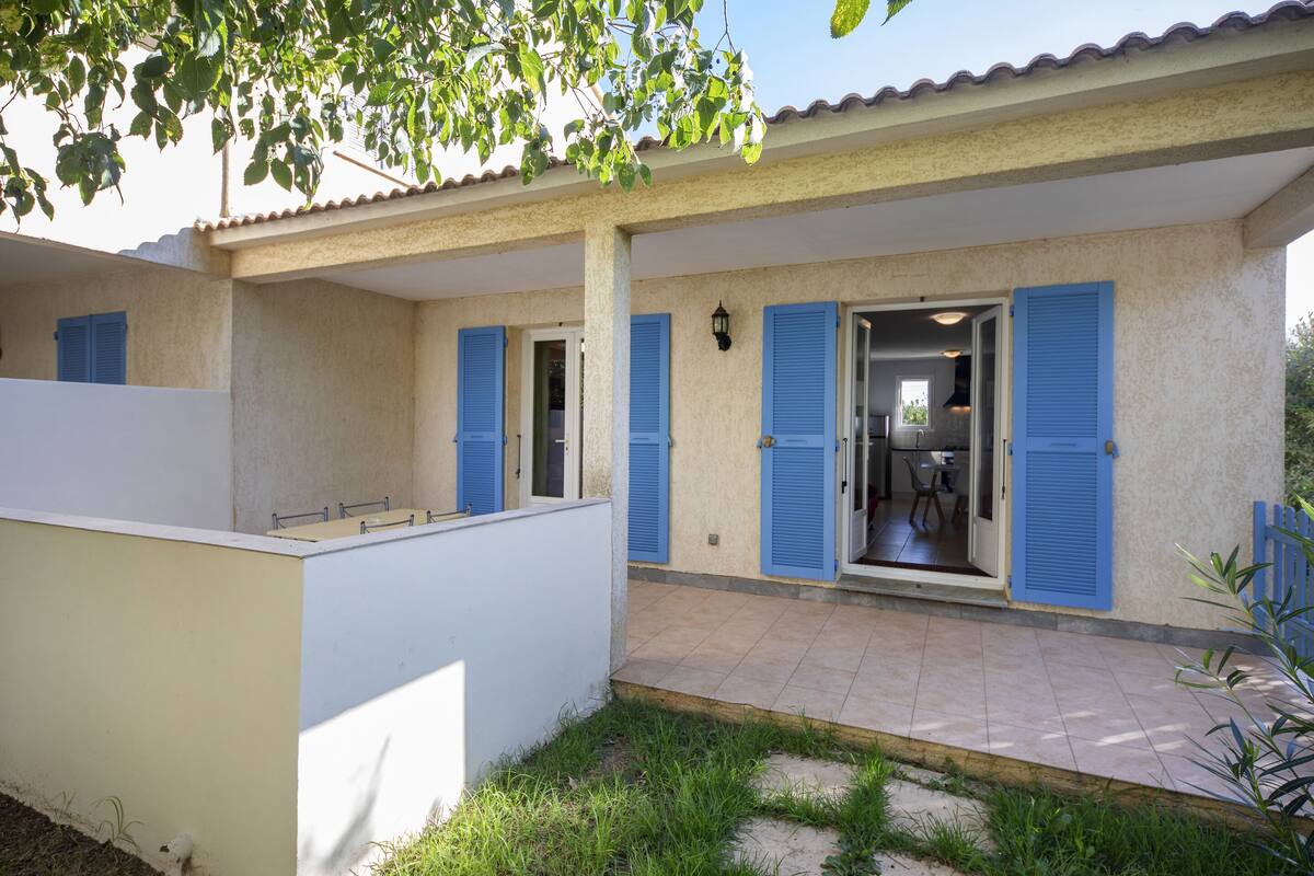 A house with a covered patio, blue shutters, and a visible kitchen area.