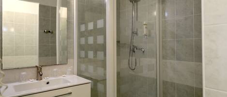 A bathroom with a glass-enclosed shower, a sink with a mirror, and a toilet.