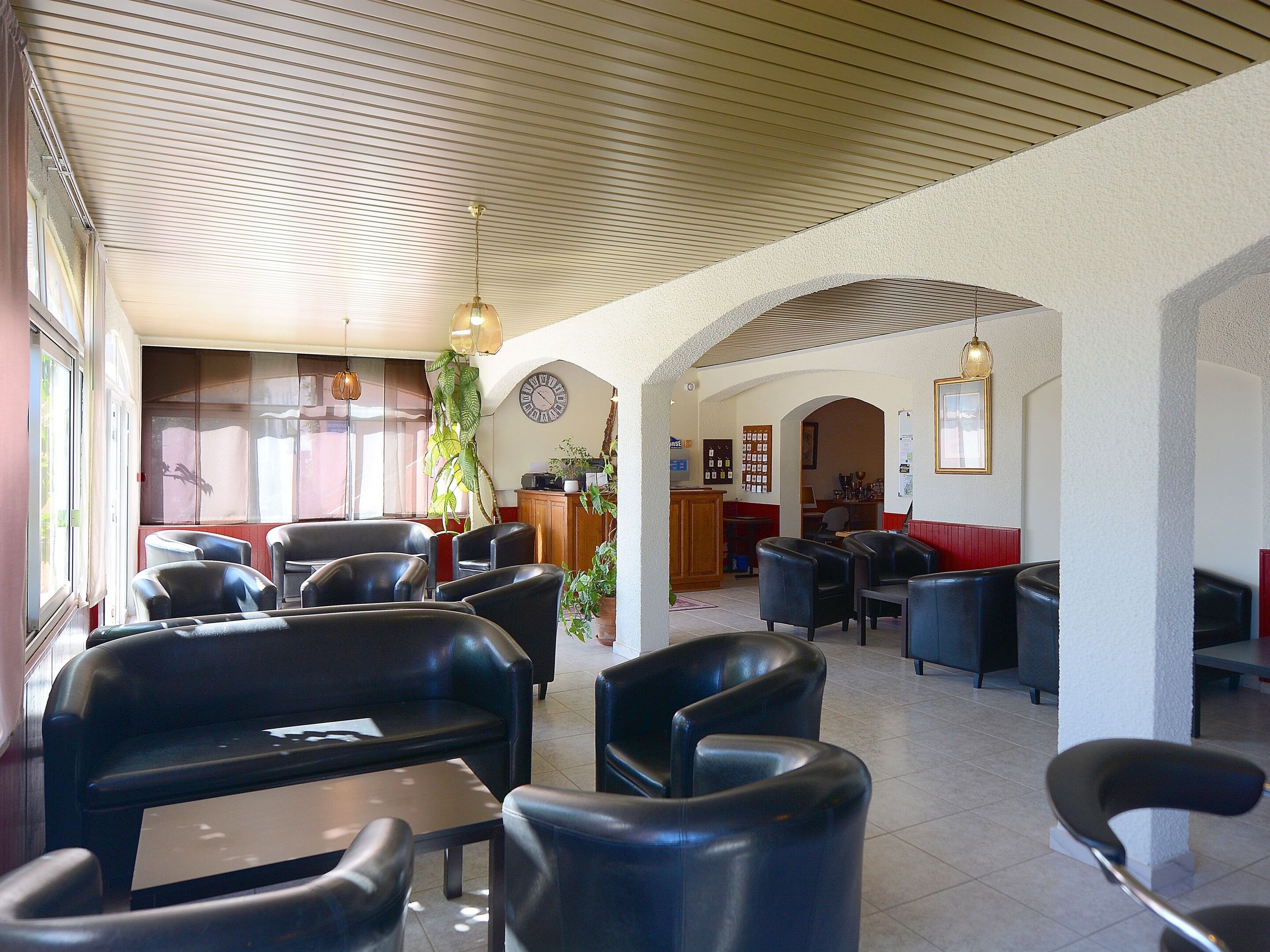 A spacious lobby with leather seating, a reception desk, and a clock on the wall.
