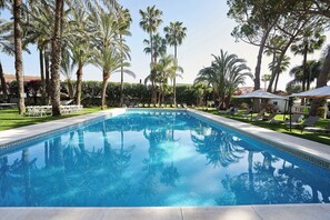 A swimming pool surrounded by palm trees and lounge chairs. - El Oasis (L'Eliana)