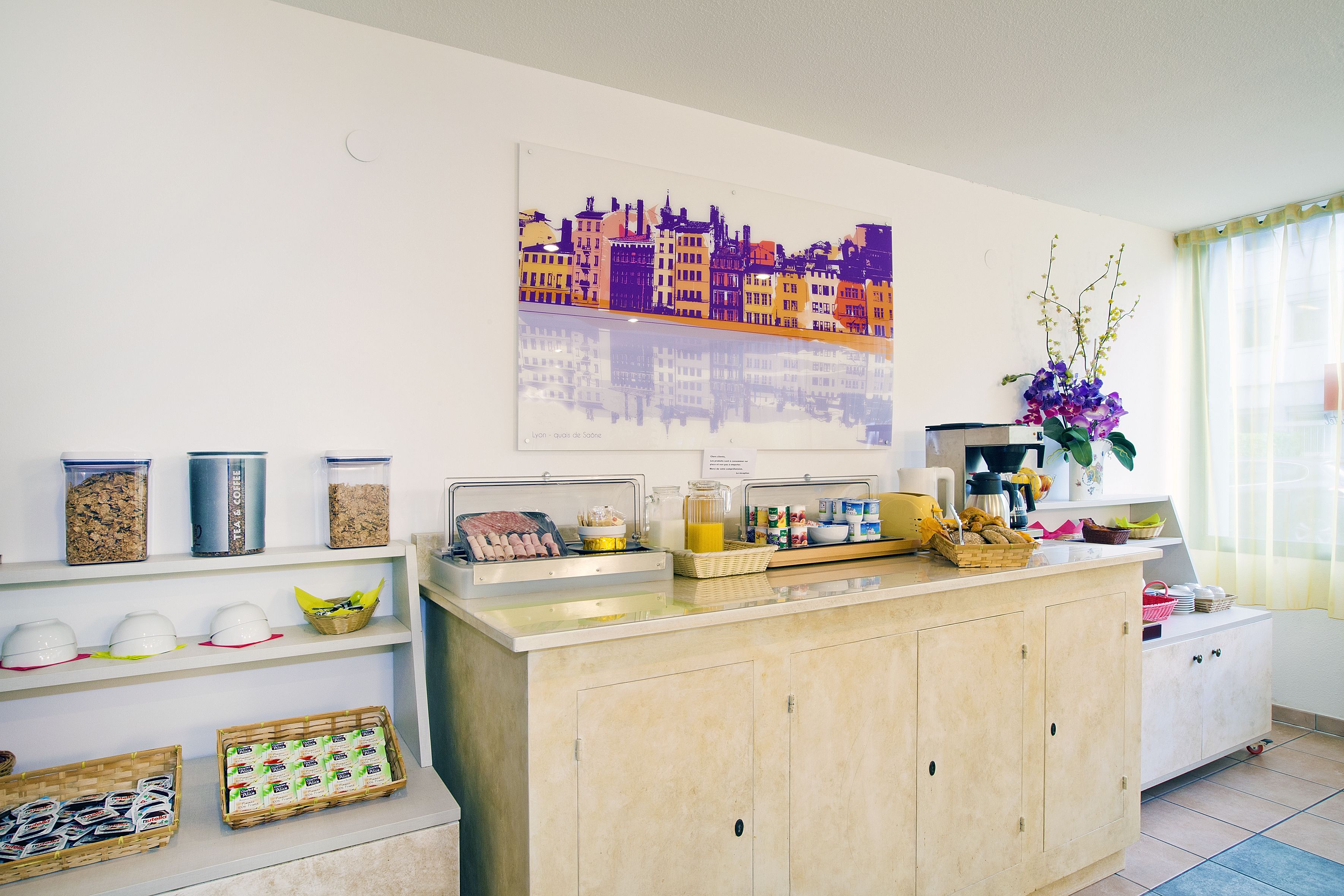 A kitchen with a countertop, shelves with food items, a coffee machine, and a decorative wall piece.