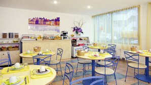 A dining area with round tables, blue chairs, and yellow placemats. - Séjours & Affaires Lyon Saint-Nicolas (Lyon)