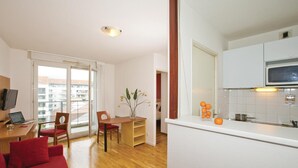 A modern apartment with a dining area, a kitchen with a microwave, and a red sofa. - Séjours & Affaires Lyon Saint-Nicolas (Lyon)