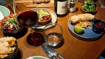 Une table à manger avec différents plats, une bouteille de vin et des couverts.