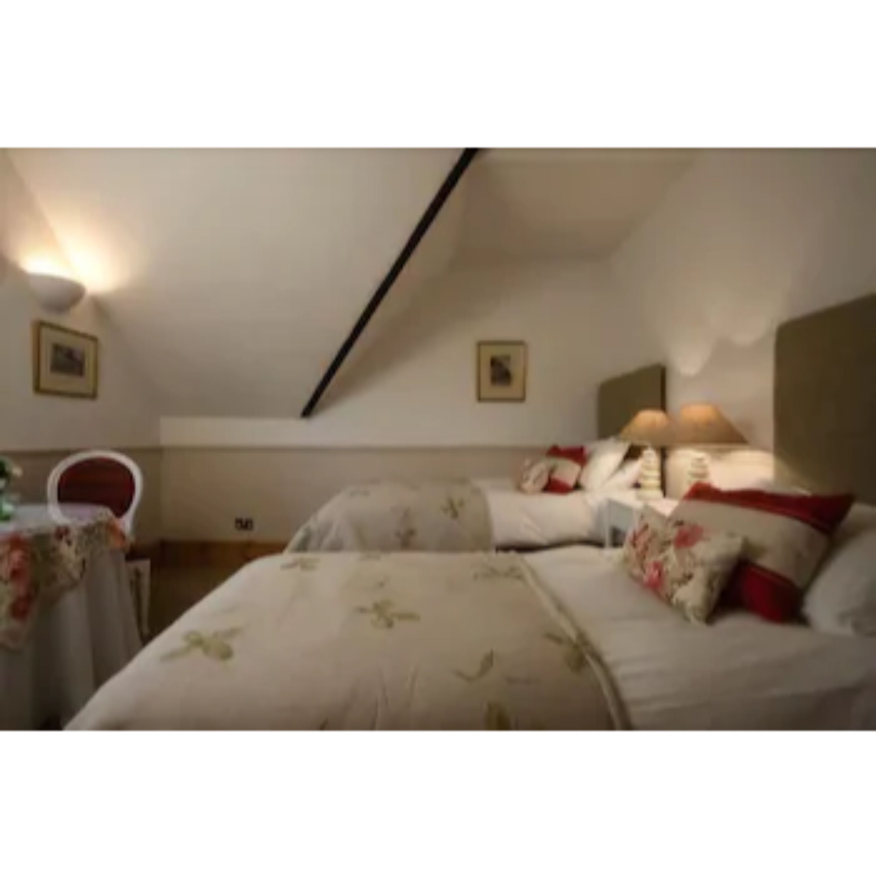Ein Schlafzimmer mit Bett, Nachttischen und einem Sessel.