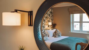 A bedroom with a bed, a bedside lamp, a potted plant, and a window with a view. - The Winning Post (Windsor)