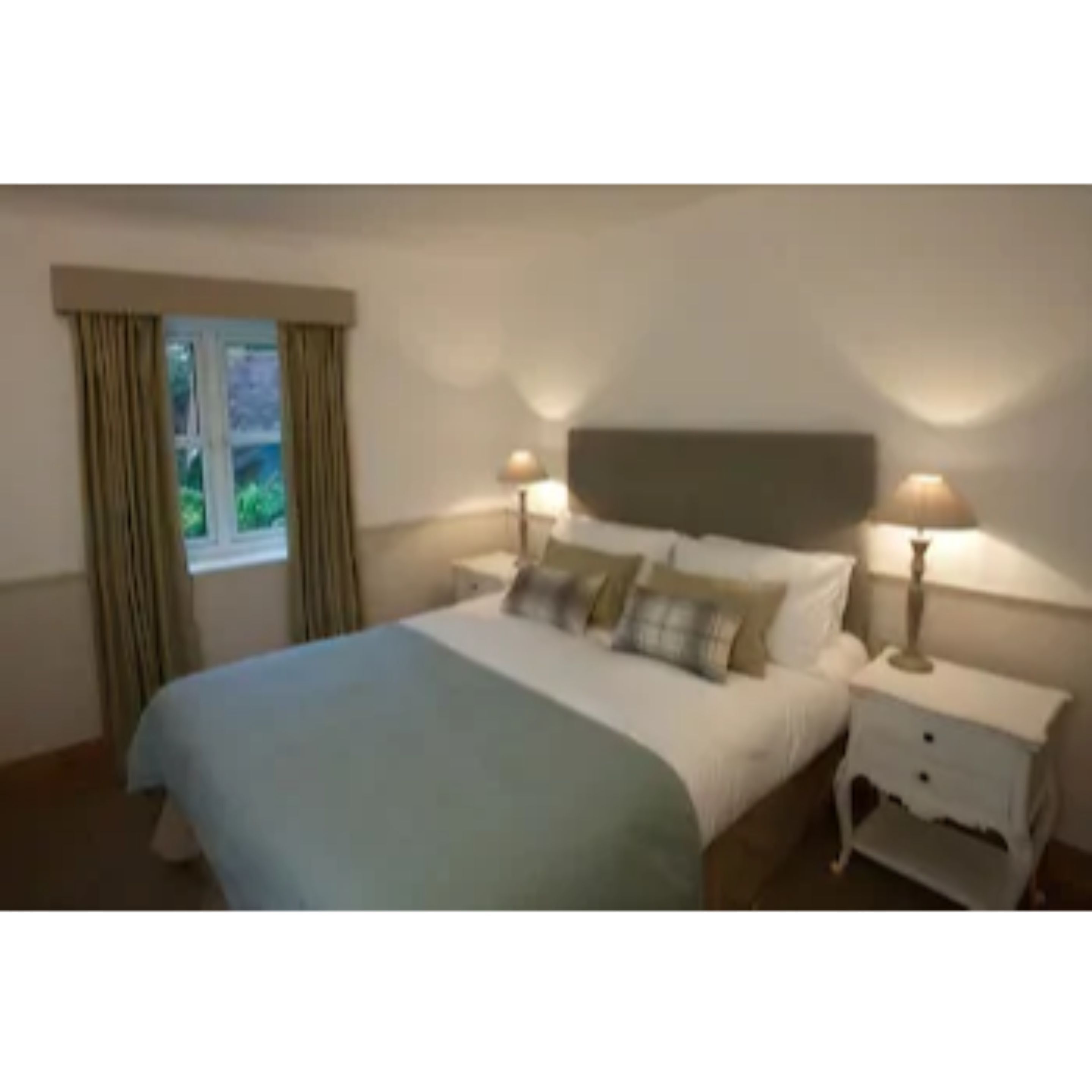 A bedroom with a bed, two bedside tables, a window with curtains, and a view of greenery outside.