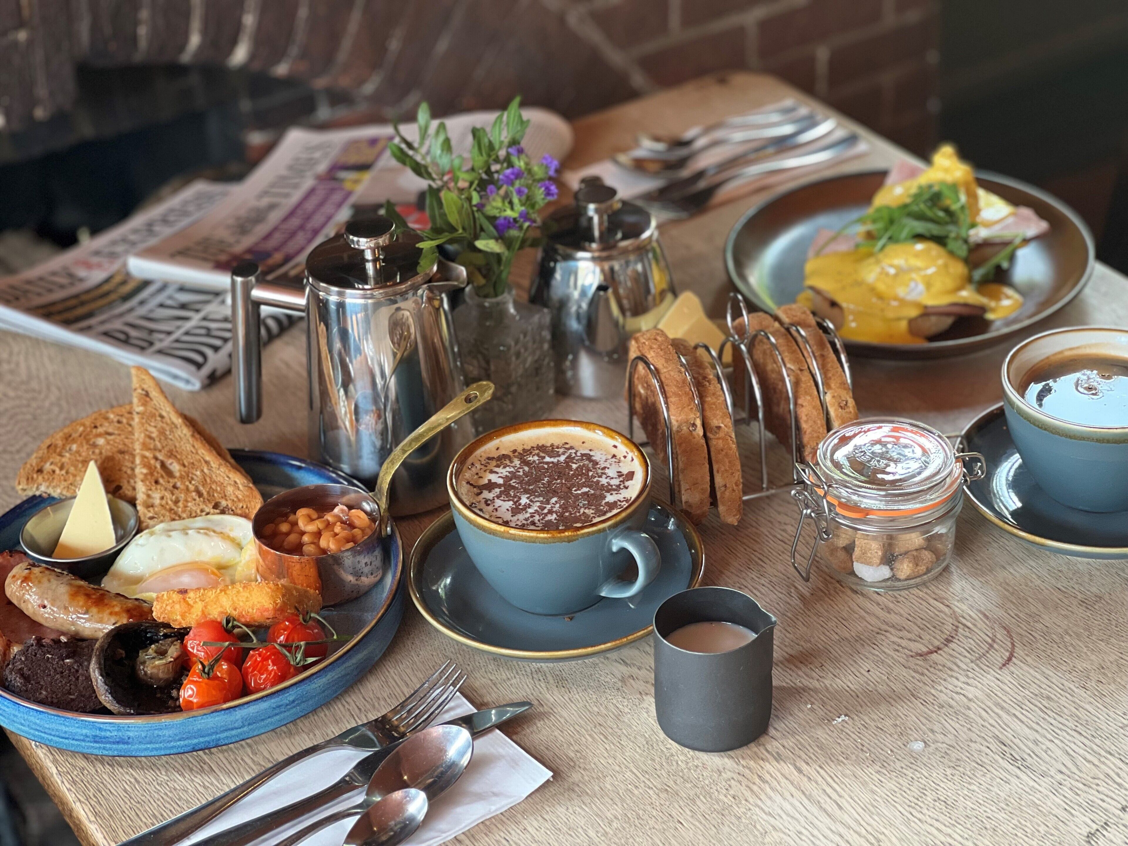 Un desayuno con diferentes platos, como tostadas, huevos y una taza de café.