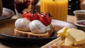 A breakfast setting with toast, tomatoes, cheese, and a glass of orange juice. - The Winning Post (Windsor)
