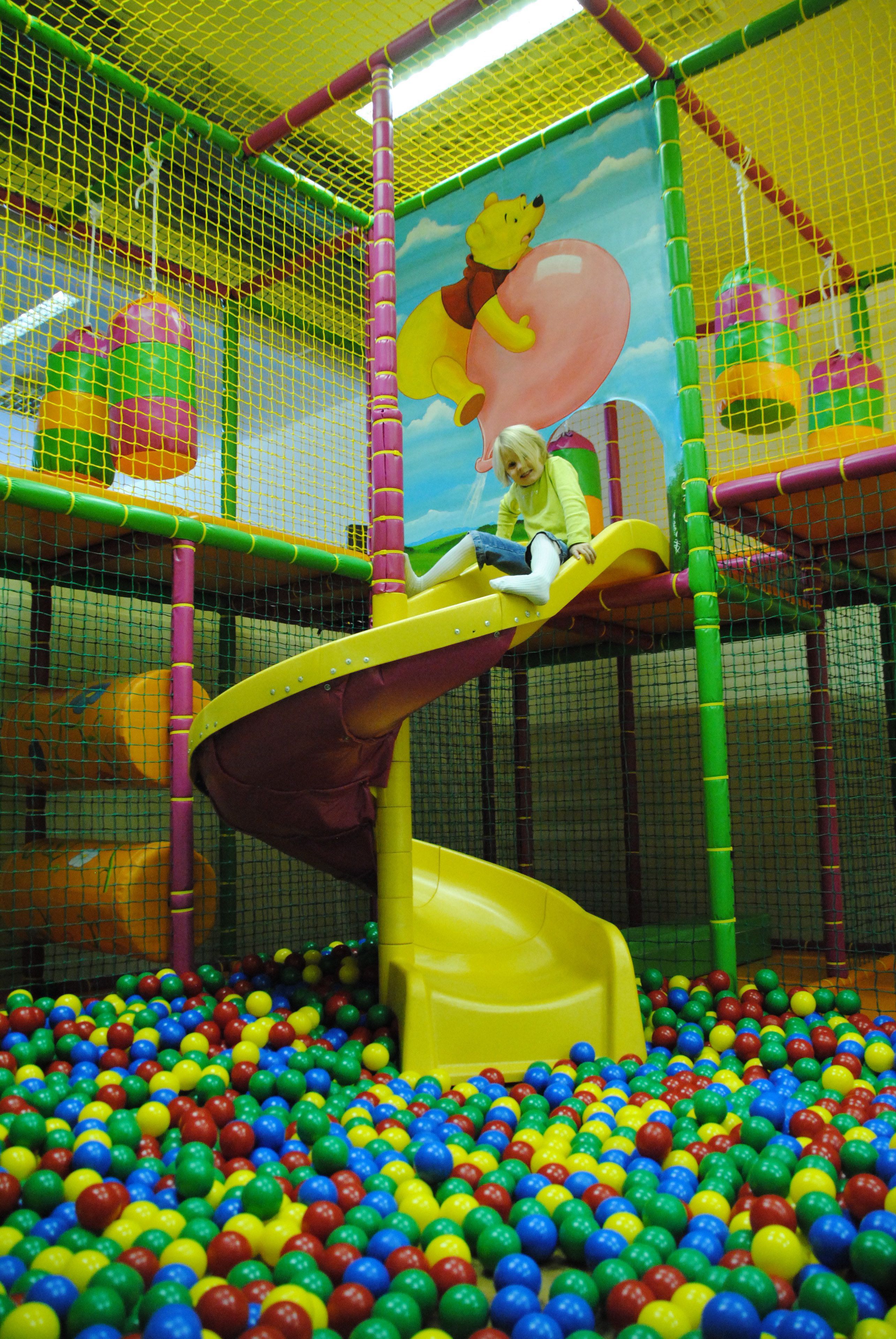 A child playing on a slide in a ball pit with colorful balls.