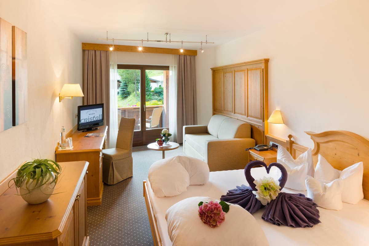 Une chambre d’hôtel équipée d’un lit, d’un bureau, d’une chaise, d’une télévision et offrant une vue sur l’extérieur.