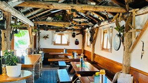 A rustic wooden interior with wooden benches and tables, a barrel, and a menu board. - Gasthaus Bonimeier (Haiming)
