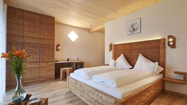 A wooden bedroom with a bed, bedside tables, a nightstand, a desk, and a wardrobe. - Gasthaus Bonimeier (Haiming)