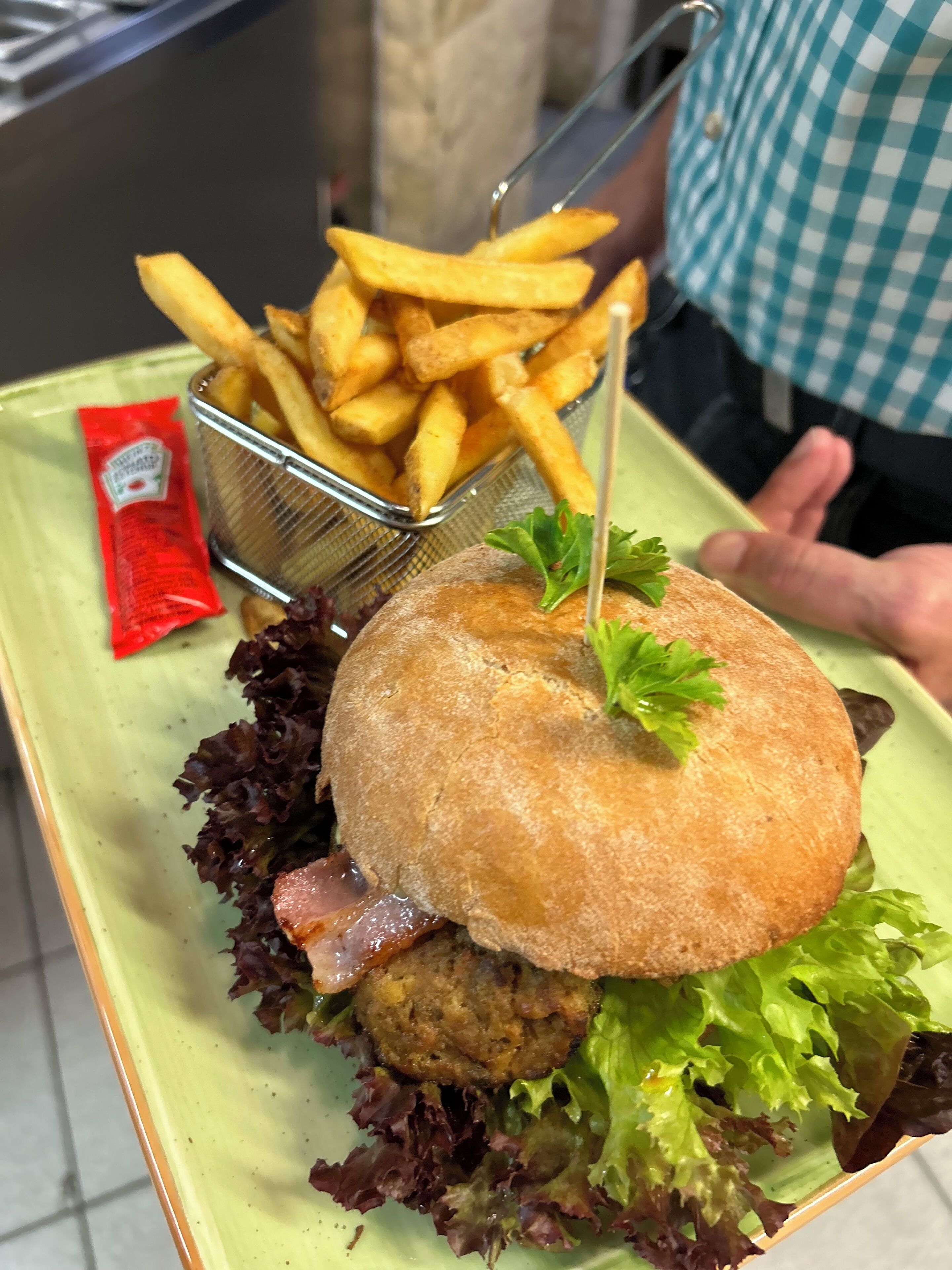 A sandwich with lettuce, a bun, and a side of fries on a plate.