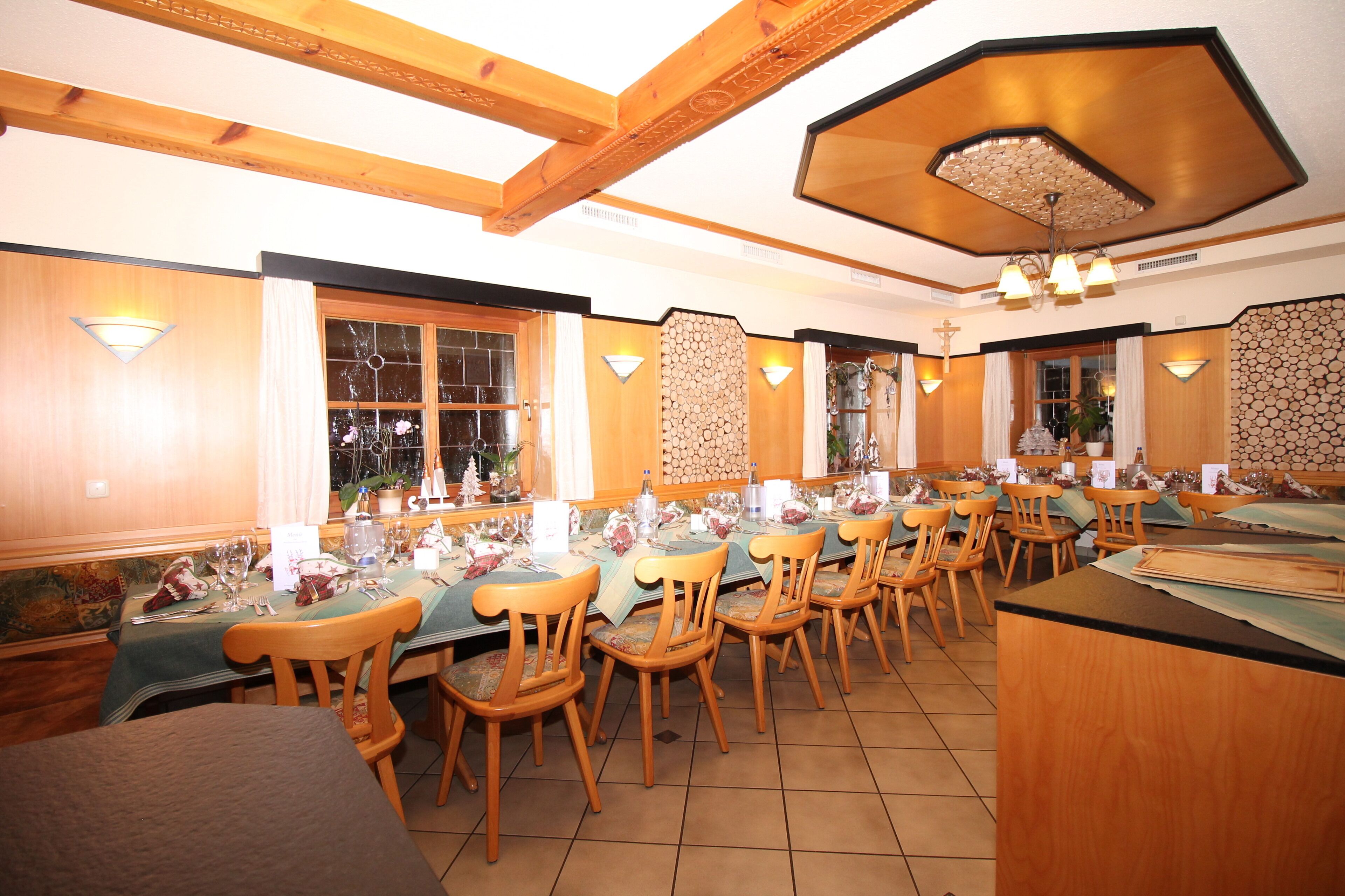 Un restaurante con vigas de madera, una mesa larga y múltiples sillas.