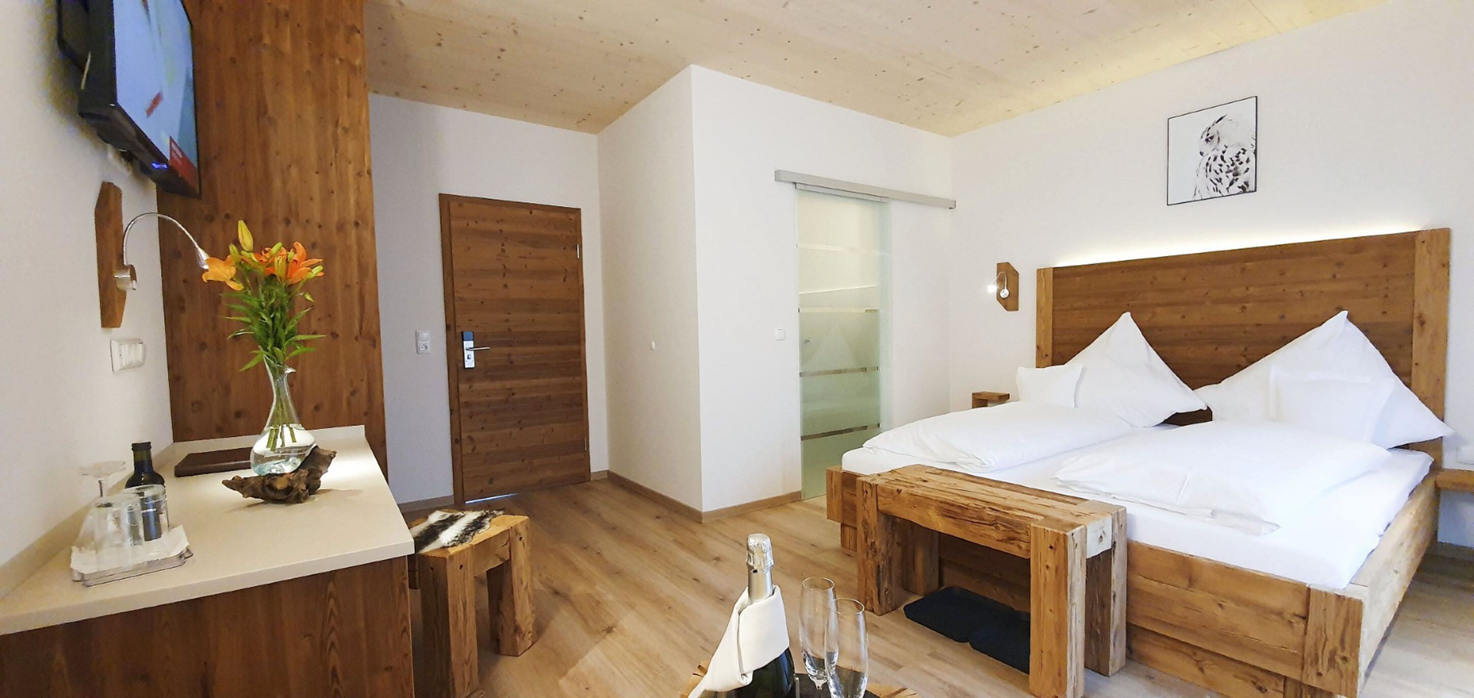 Habitación de hotel con una cama y un escritorio de madera, un televisor y una puerta.