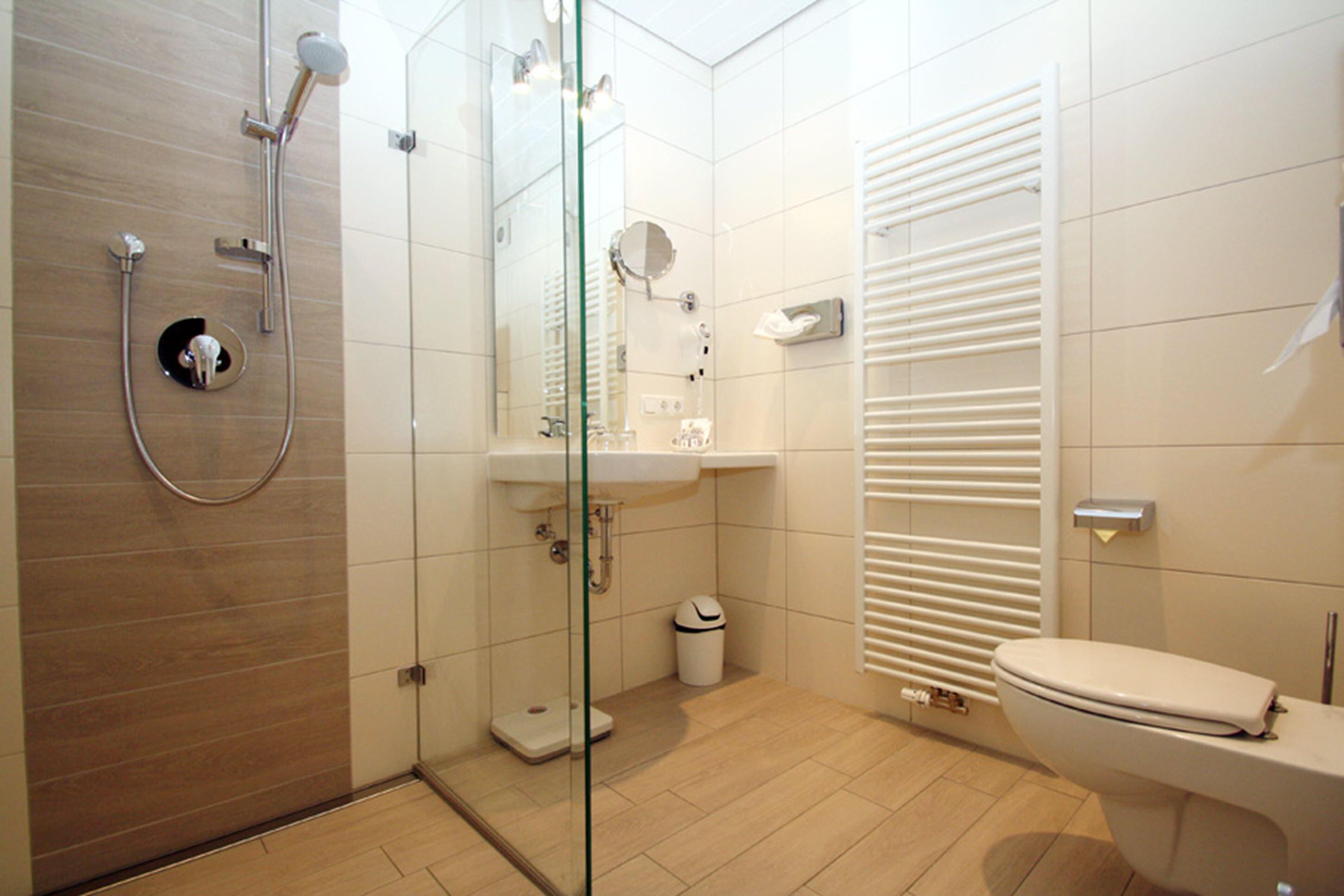 Un baño moderno con cabina de ducha de vidrio, un lavabo blanco y un inodoro.