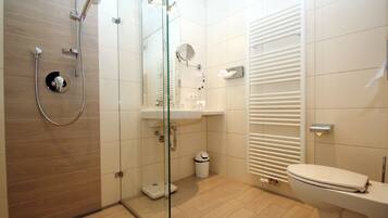 Un baño moderno con cabina de ducha de vidrio, un lavabo blanco y un inodoro.
