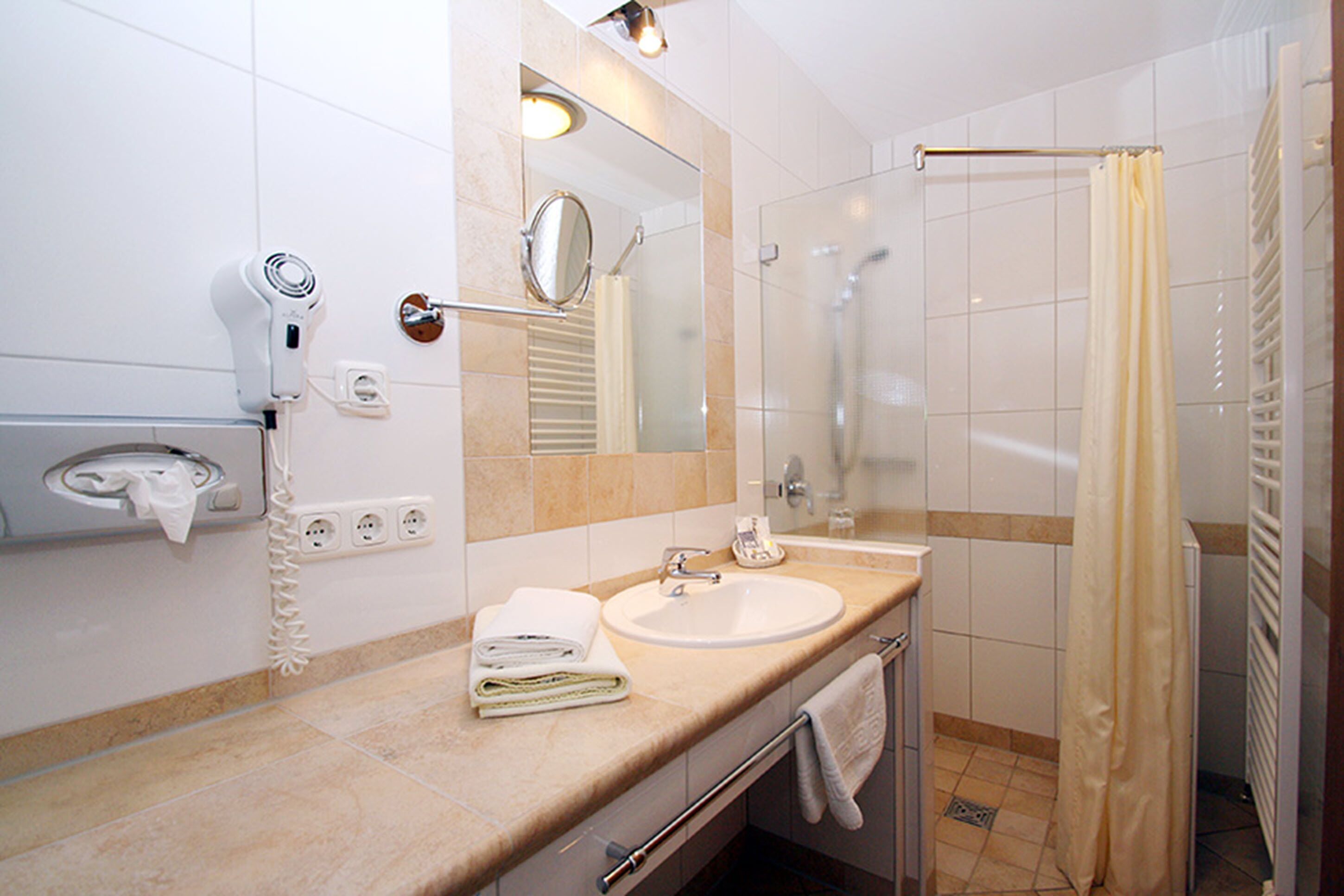 Ein modernes Badezimmer mit Waschbecken, Spiegel und Dusche.