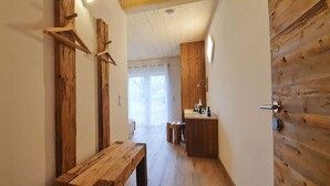 A narrow hallway with wooden beams and a bench. A small table and a sink area are visible in the background. - Gasthaus Bonimeier (Haiming)