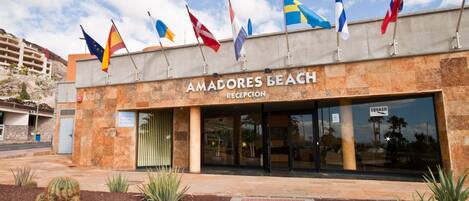 Un edificio con varias banderas, una recepción y un letrero que dice "AMADORES BEACH RECEPTION".