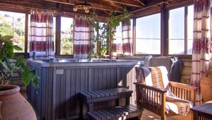 A wooden deck with a hot tub, wooden benches, and a chair. - Stone Village (Mylopotamos)