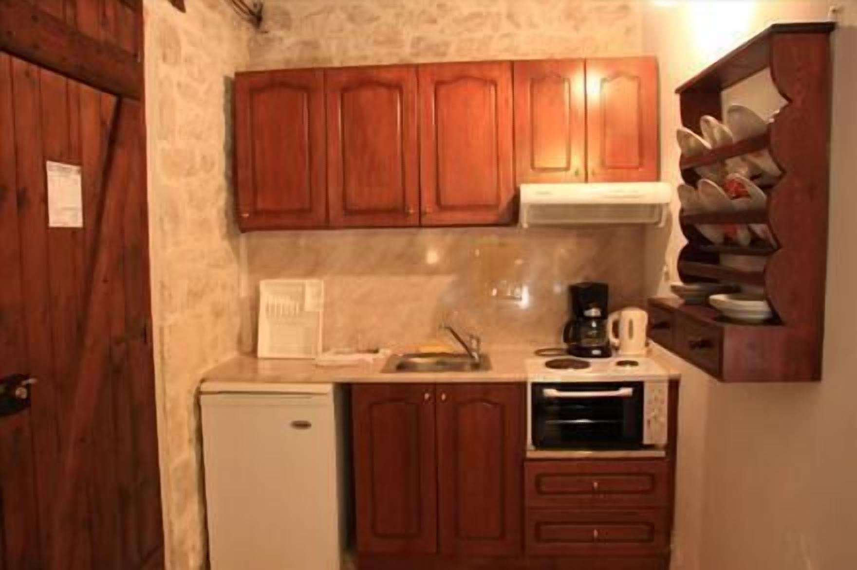 A compact kitchen with wooden cabinets, a coffee maker, and a microwave.