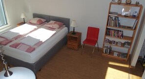 A bedroom with a bed, bedside tables, a red chair, and a bookshelf. - Estinn Apartment (Tallinn)