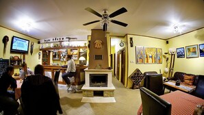 A bar area with a fireplace, a clock, and a seating area with a couch and table. - Penzion Plesnivec (Poprad)