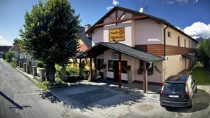 A building with a sign reading "Pension Plesnivec" and a car parked in front. - Penzion Plesnivec (Poprad)