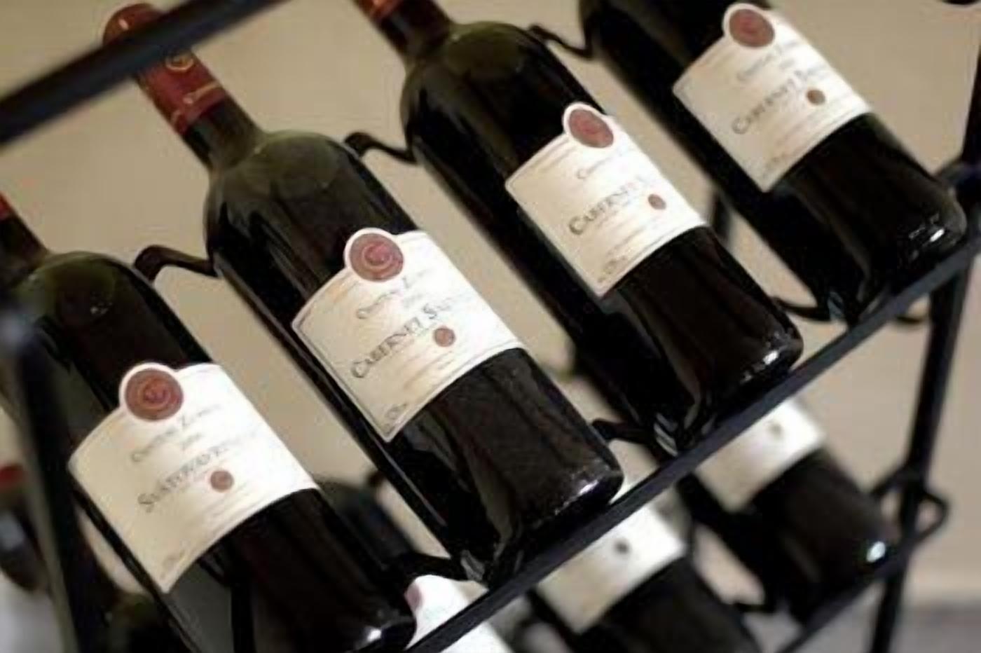 Une étagère remplie de bouteilles de vin, toutes étiquetées, probablement située dans une cave à vin ou dans un espace de stockage.