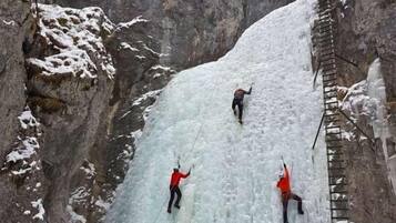 A group of people ice climbing on a steep, snow-covered rock face with a ladder.