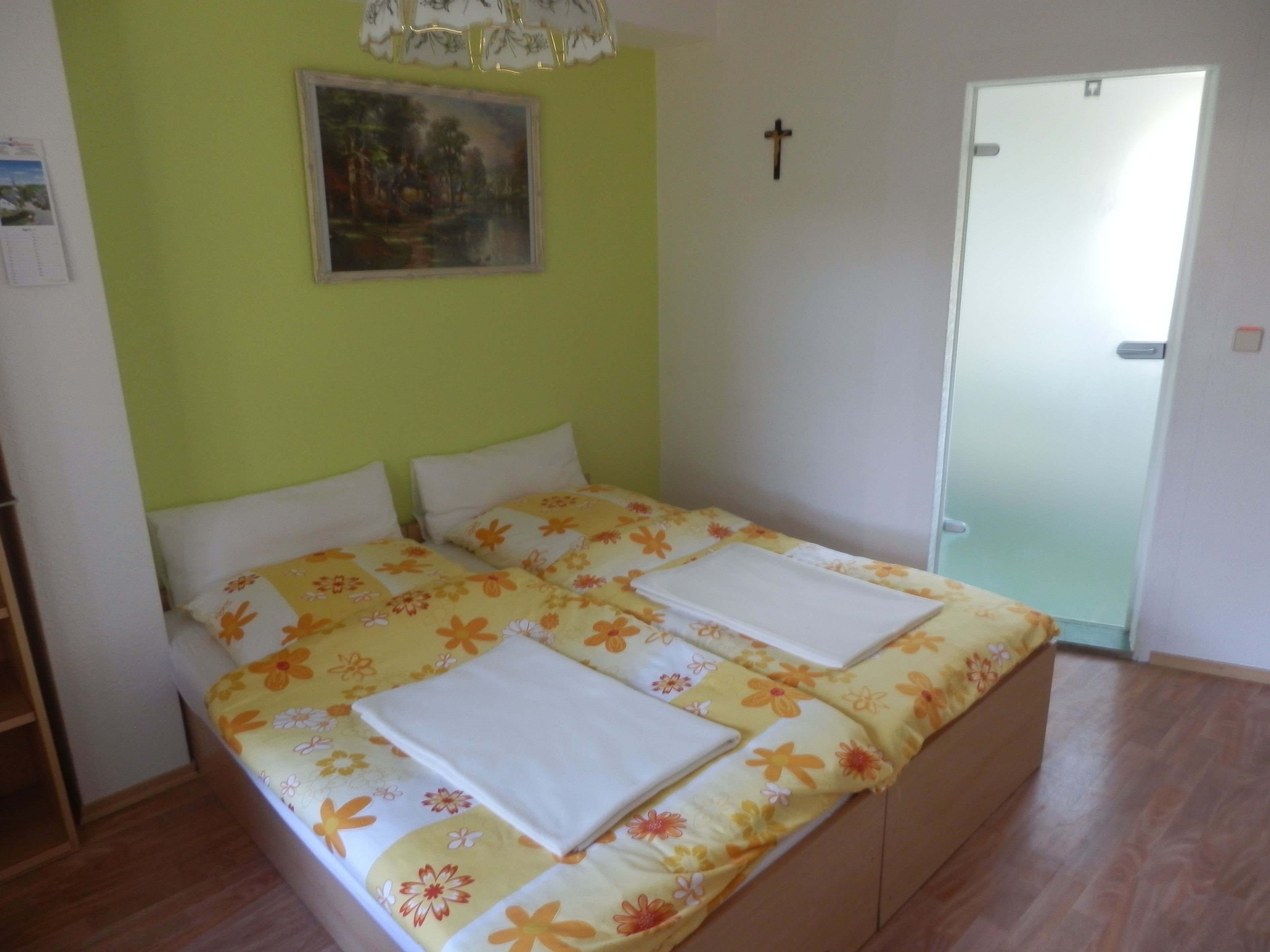 A bedroom with a bed, a painting on the wall, and a door.