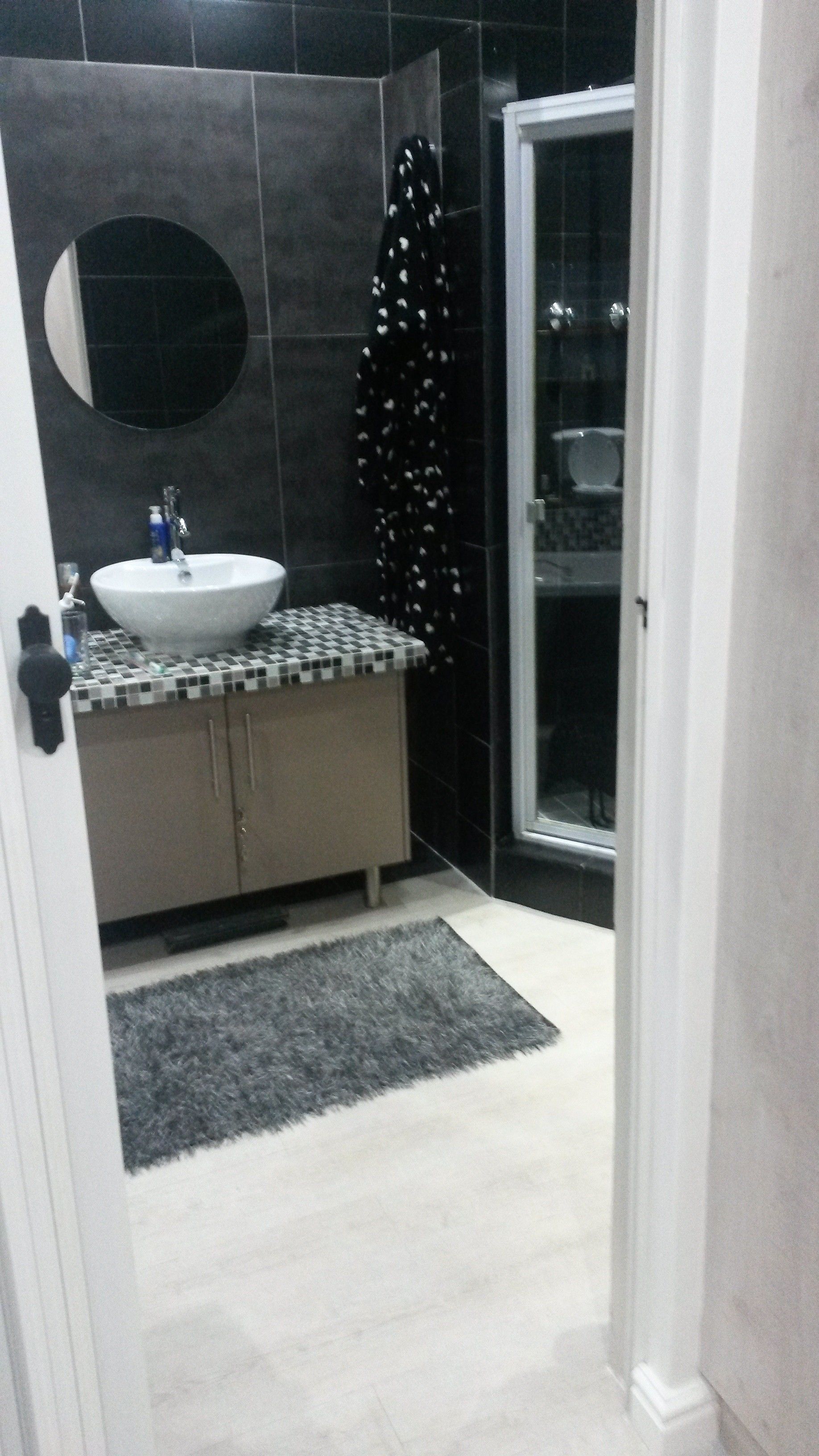 A bathroom with a white sink, a mirror, and a shower area.