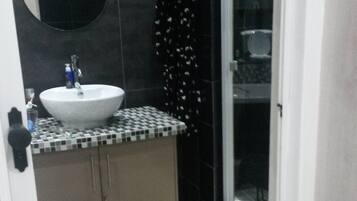 A bathroom with a white sink, a mirror, and a shower area.